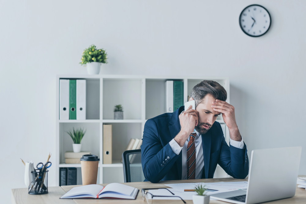 Uomo in ufficio che si tocca la testa in modo nervoso
